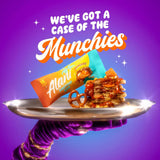 AlaniNu Protein Bar Munchies — wrapped bar and caramel-drizzled stack on a silver tray held by a gloved hand